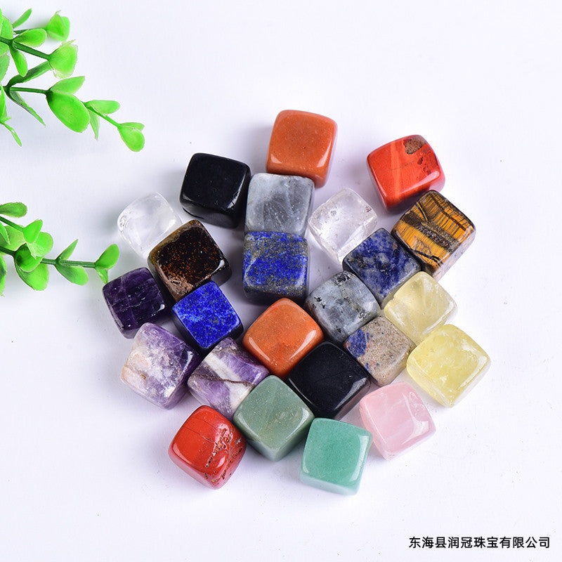 Assorted colorful gemstones on a white background with green leaves.