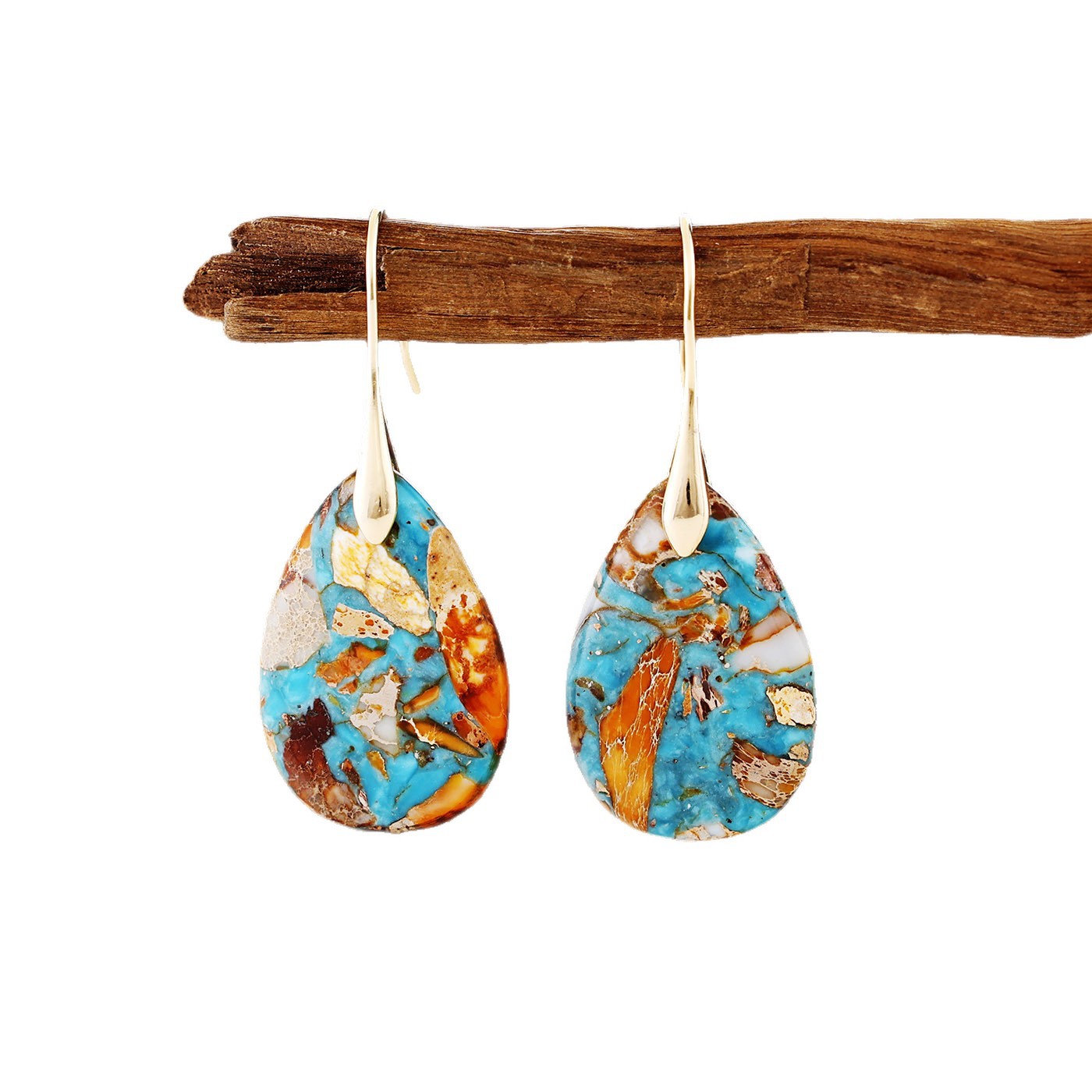 Teardrop-shaped earrings with a colorful pattern hanging on a wooden stick against a white background.