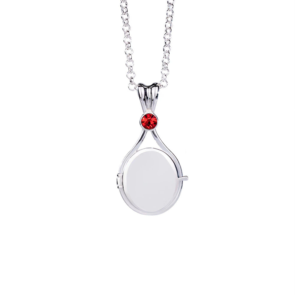 Silver necklace with a round pendant featuring a red gemstone on a white background