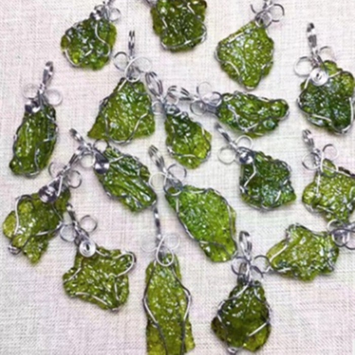 Green stone pendants with silver loops on a white fabric background