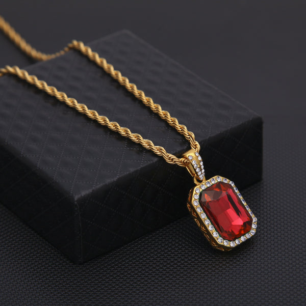 Gold necklace with a red gemstone pendant on a black background