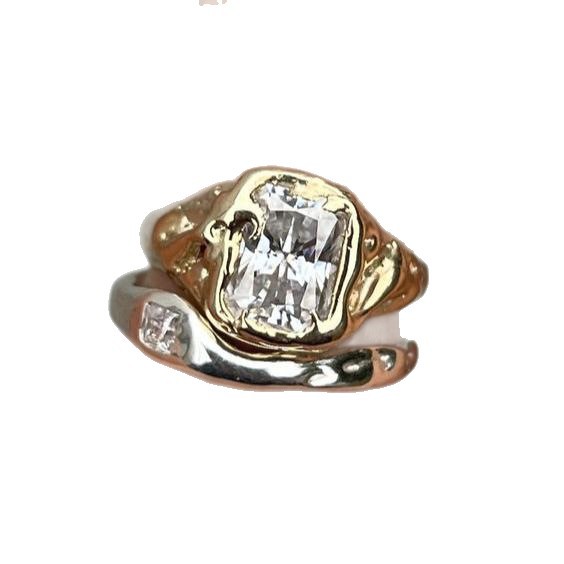 Gold and silver ring with a large diamond and smaller diamonds on a white background