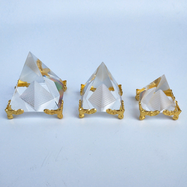 Three crystal pyramid-shaped objects with gold bases on a light blue background