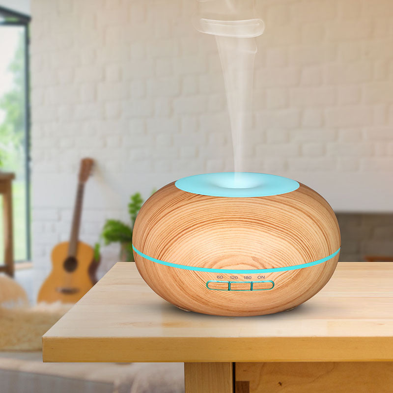 Wooden diffuser emitting mist on a table with a guitar and plant in the background