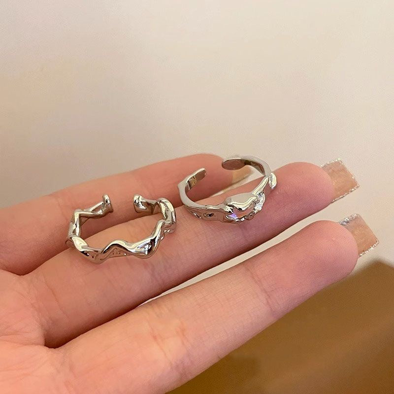 Two silver open rings on a person's finger against a neutral background