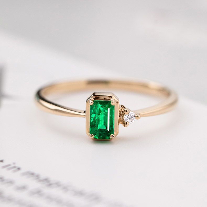 Gold ring with a green gemstone on a light background