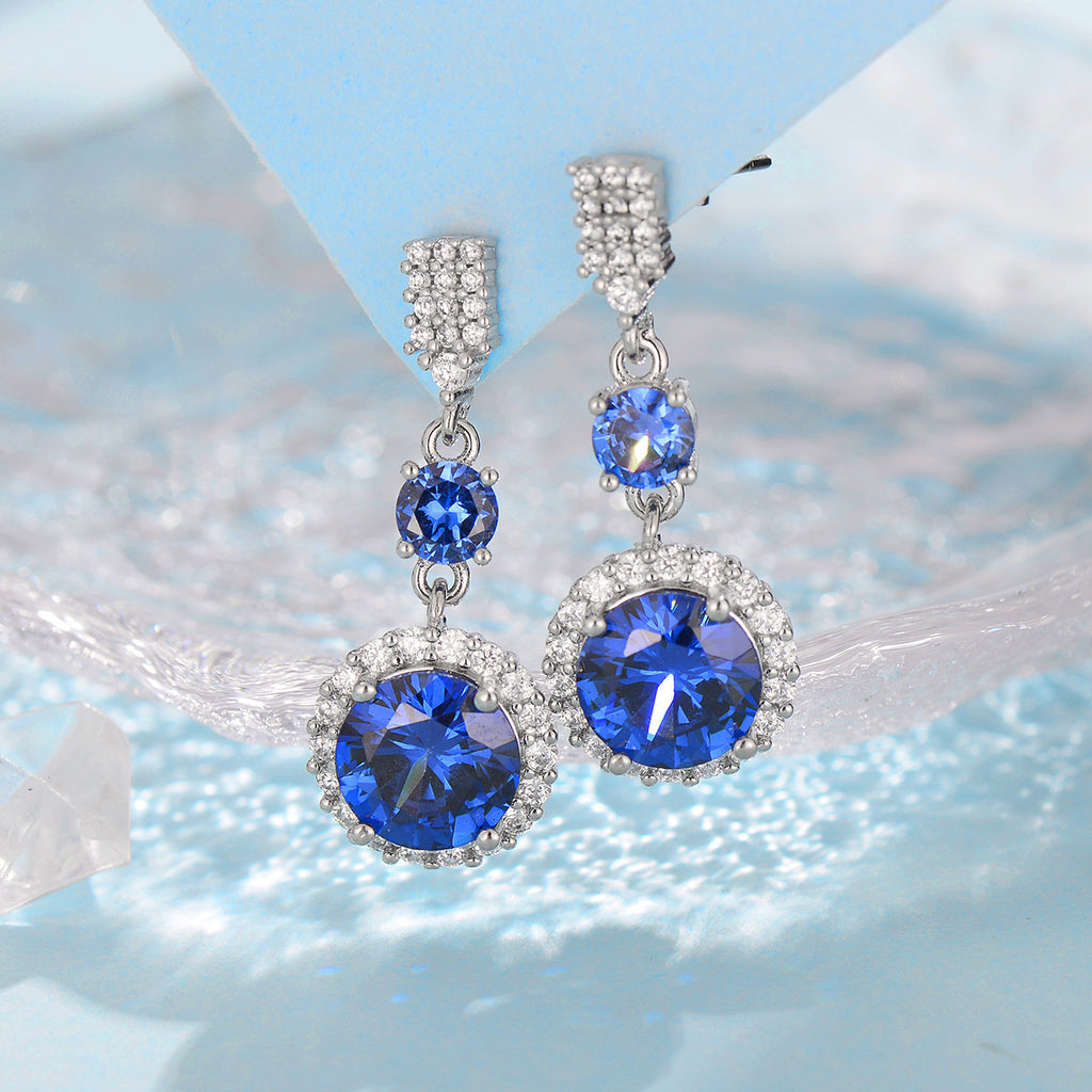 Pair of blue gemstone earrings with silver accents on a light blue background