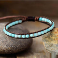 Turquoise beaded bracelet on brown leather strap on a stone surface