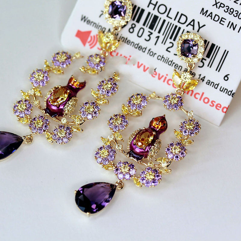 Ornate earrings with purple and gold stones on a white background