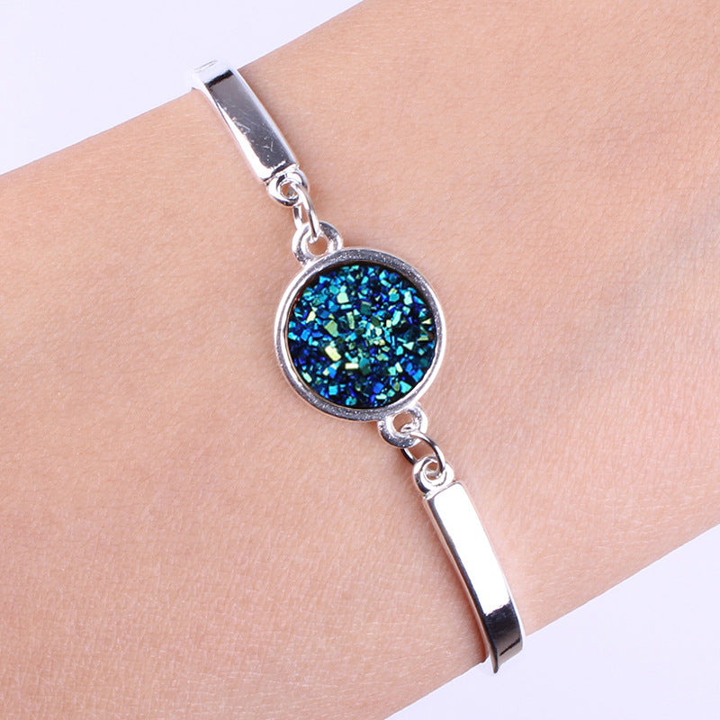 Silver bracelet with a blue gemstone on a wrist against a white background