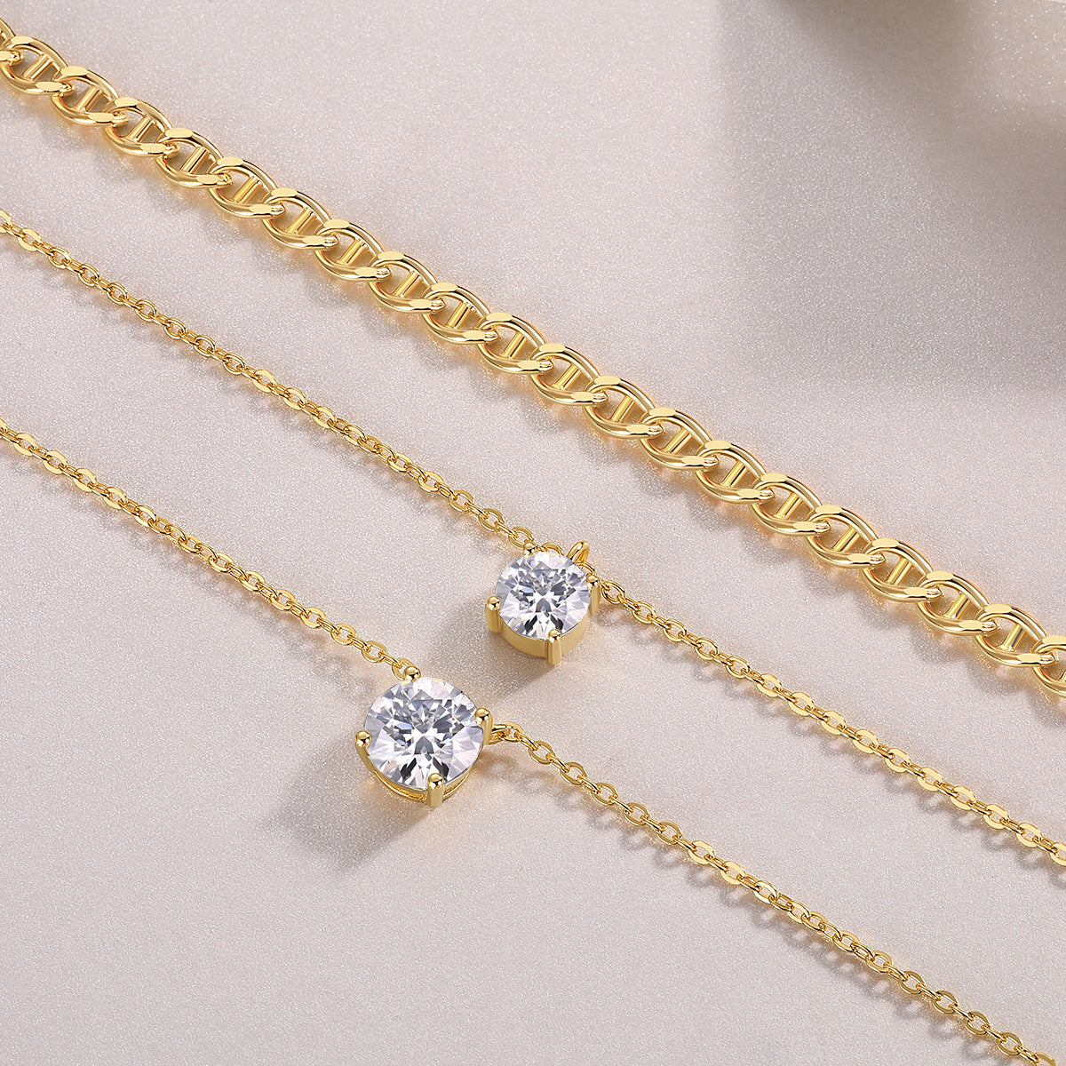 Two gold necklaces with diamond pendants on a light beige background