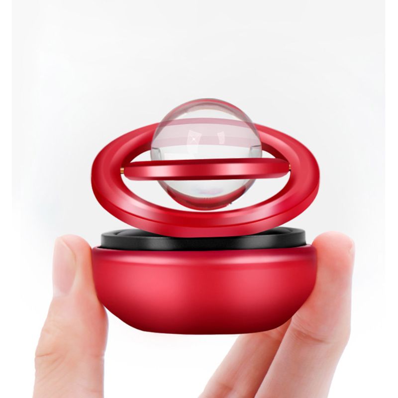 Red and black device with a transparent sphere held between fingers on a white background