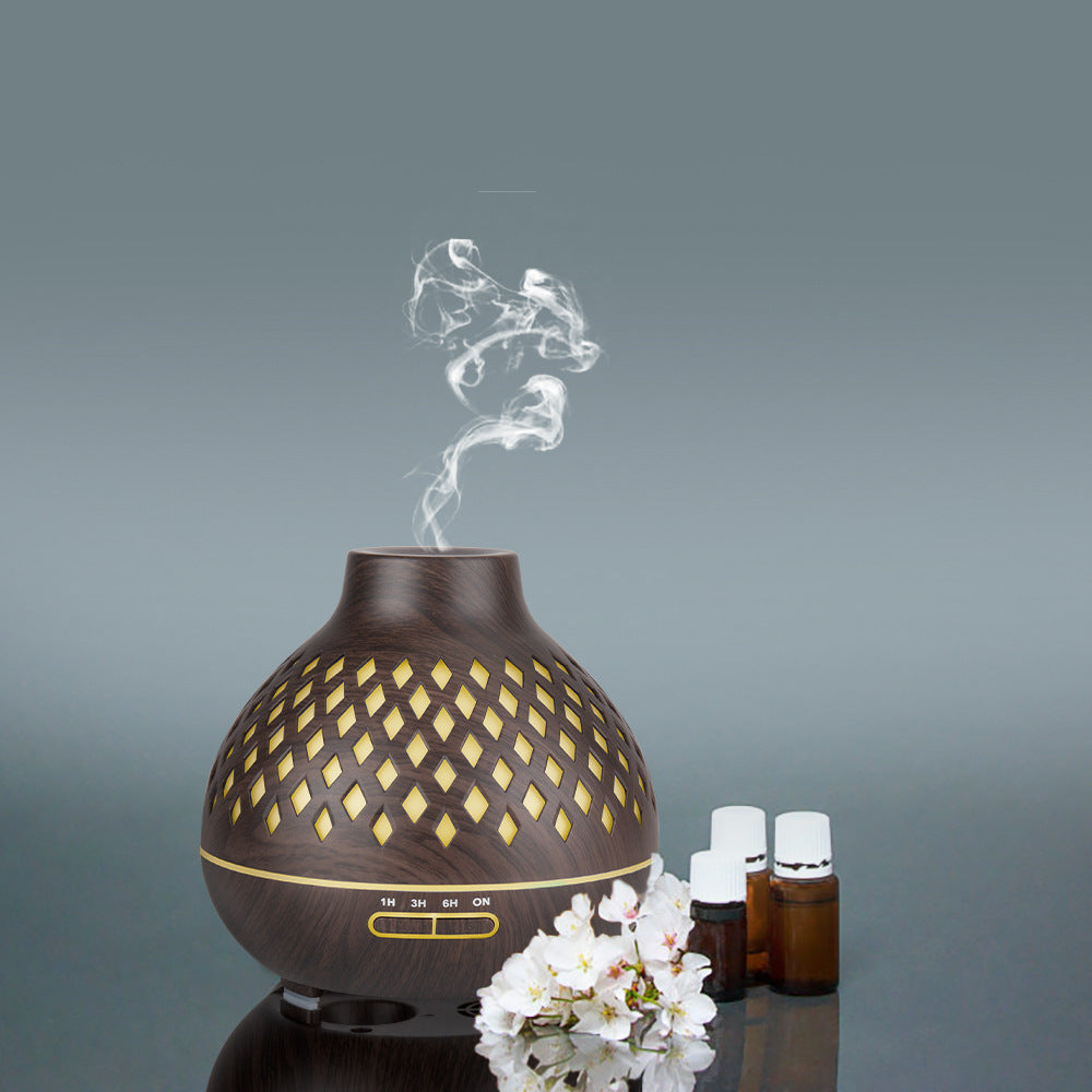 Wooden diffuser with steam and essential oil bottles on a gray background