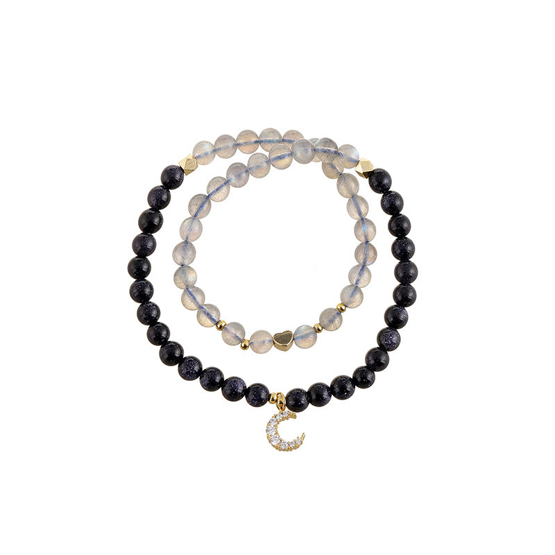 Set of two beaded bracelets with moon charm on a white background