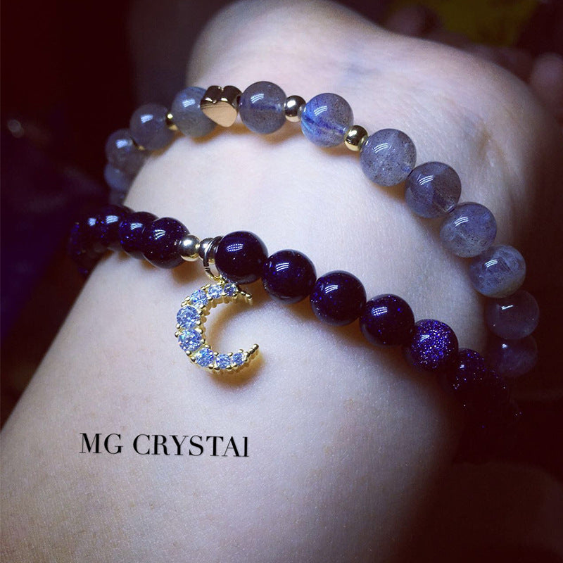 Two beaded bracelets on a wrist with 'MG Crystai' branding.