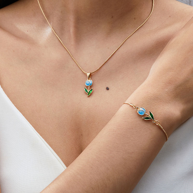 Gold necklace and bracelet with blue gemstones on a person wearing a white top.