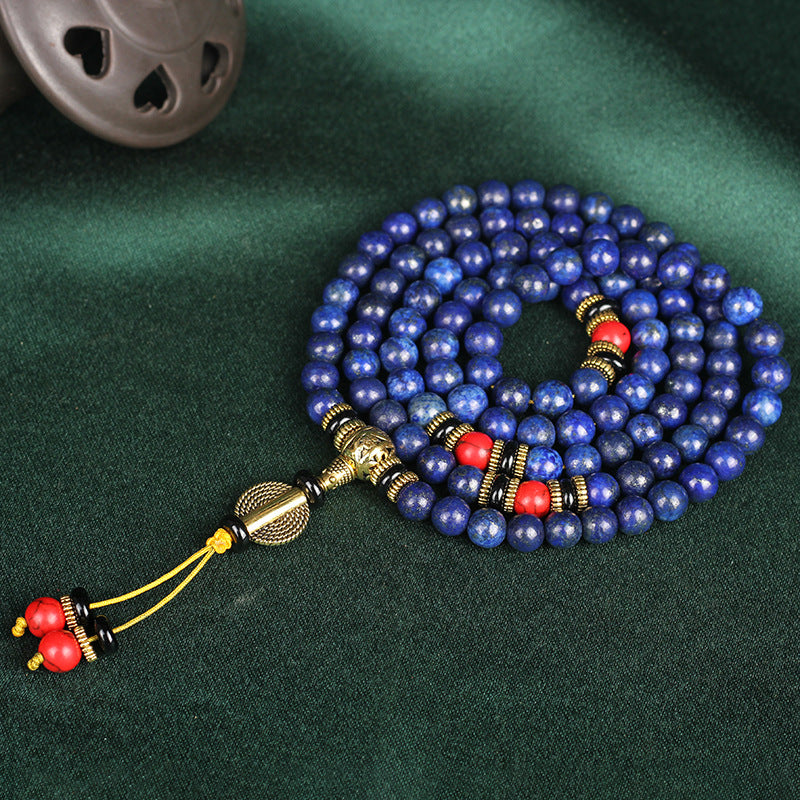 Blue beaded necklace with gold and red accents on a green fabric background