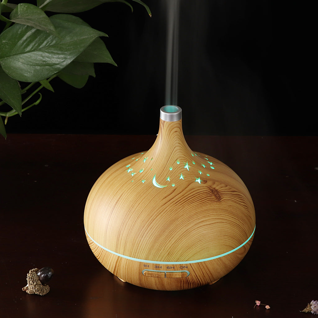 Wooden diffuser emitting mist on a dark surface with a plant in the background