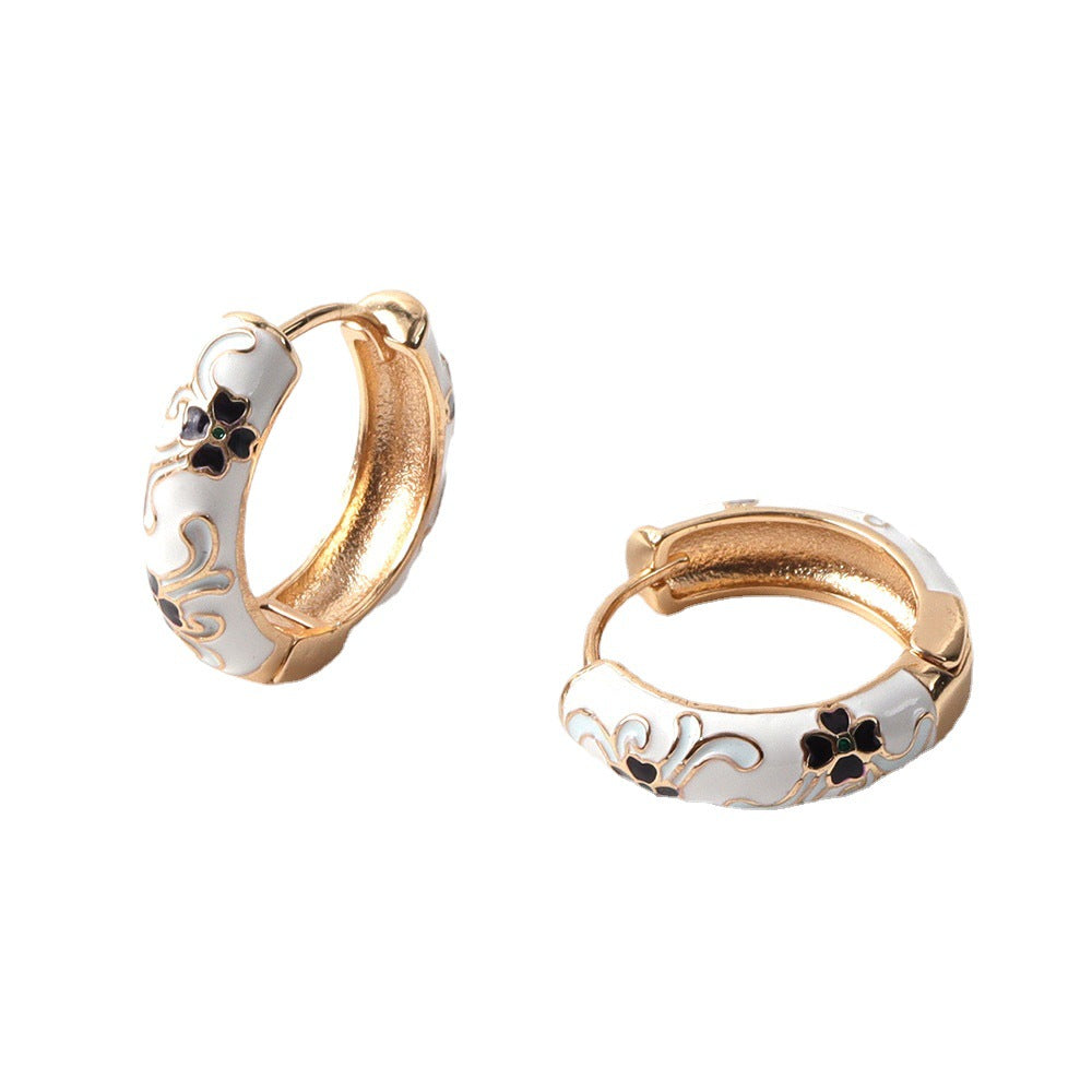 Gold hoop earrings with floral designs on a white background