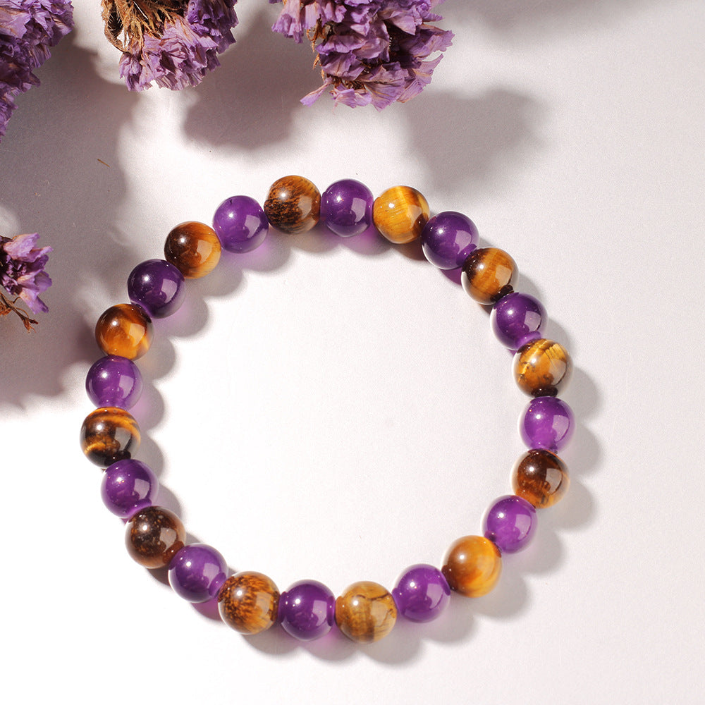 Multicolored beaded bracelet on a white surface with purple flowers