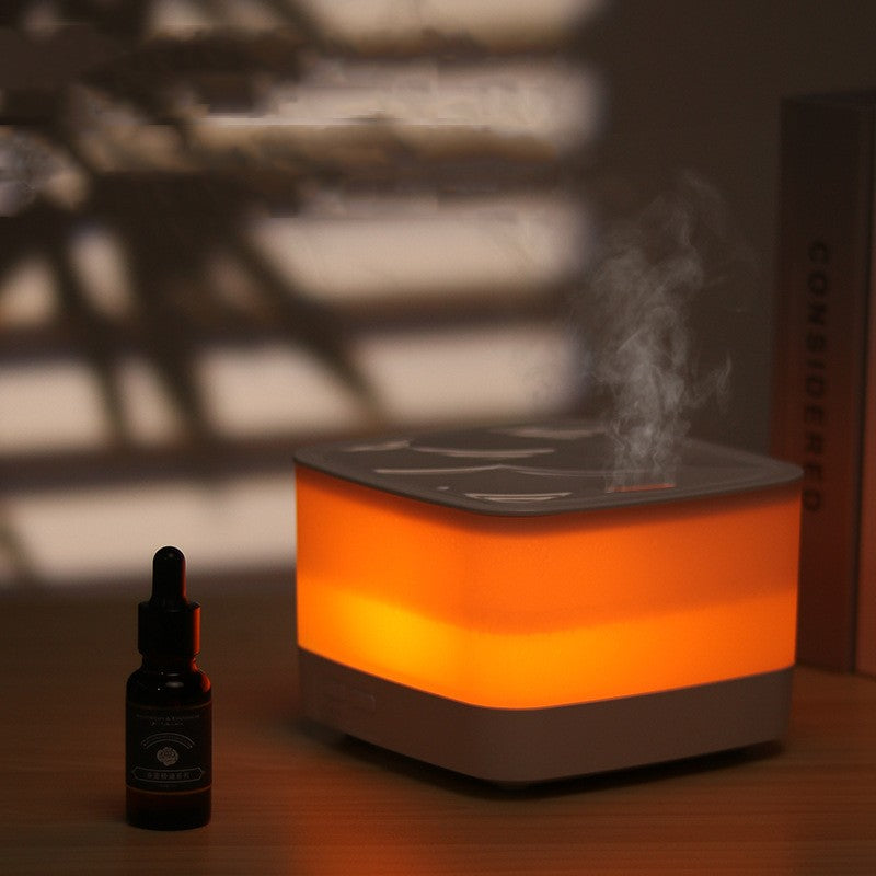 Aromatherapy diffuser emitting steam with a bottle next to it on a wooden surface.