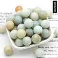 White bowl filled with greenish-beige beads on a newspaper background