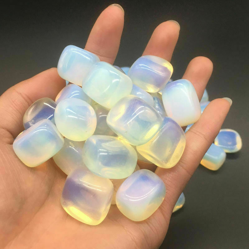 Hand holding a collection of translucent, multicolored stones against a dark background