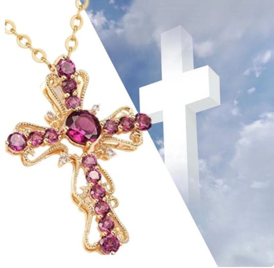 Gold cross necklace with pink gemstones against a blue sky background
