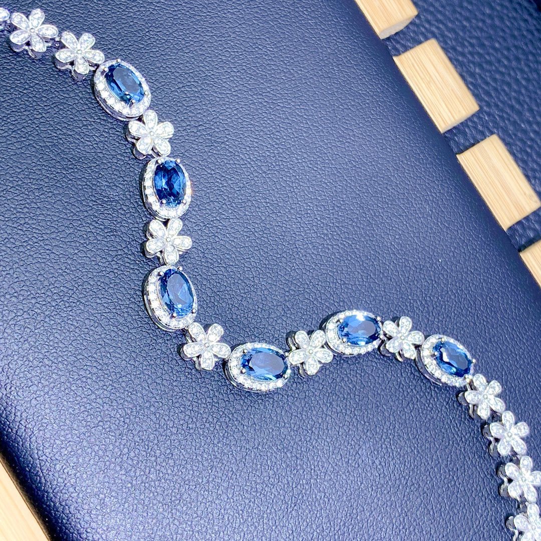 Necklace with blue gemstones and floral designs on a textured blue surface