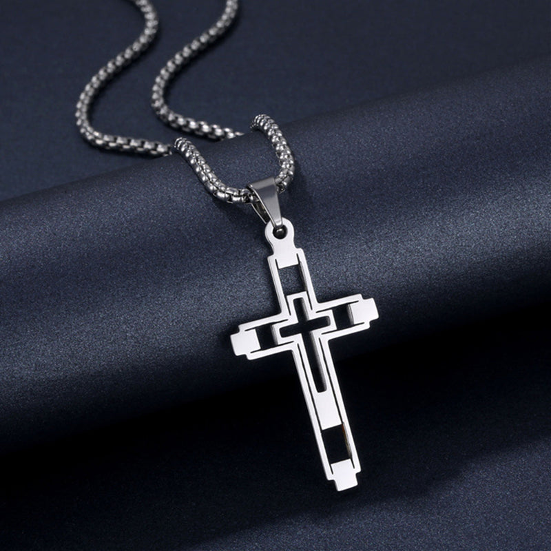 Silver cross pendant necklace on a dark fabric background