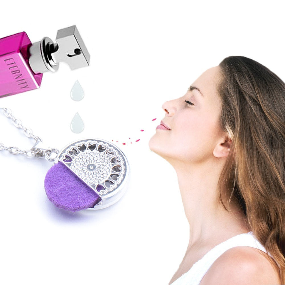 Woman smelling a perfume bottle with a purple and silver pendant on a white background