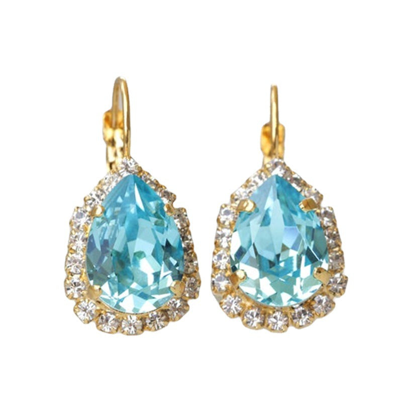 Pair of earrings with blue teardrop stones and gold accents on a white background