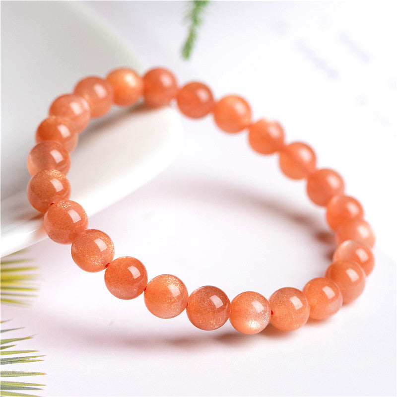 Orange beaded bracelet on a white background with green leaves