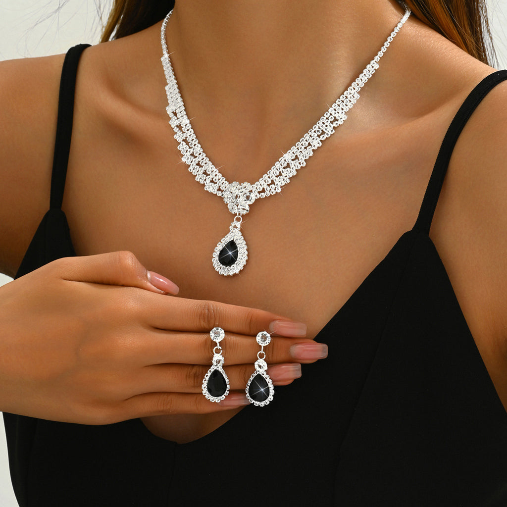 Jewelry set with necklace, earrings, and ring featuring black stones on a model wearing a black top.
