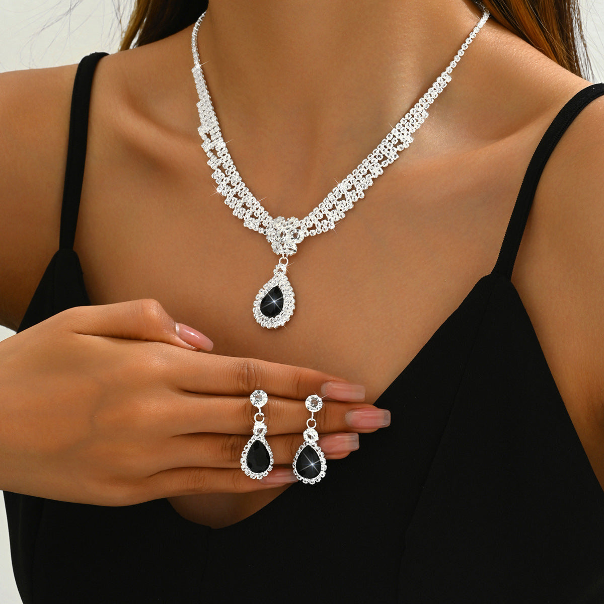 Jewelry set with necklace, earrings, and ring featuring black stones on a model wearing a black top.