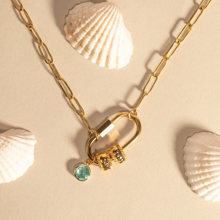 Gold necklace with a heart lock and key pendant on a beige background with shells.