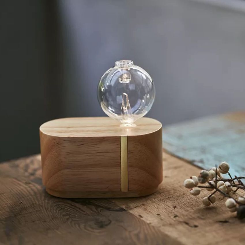 Wooden base with a clear glass sphere containing a light bulb on a wooden surface.