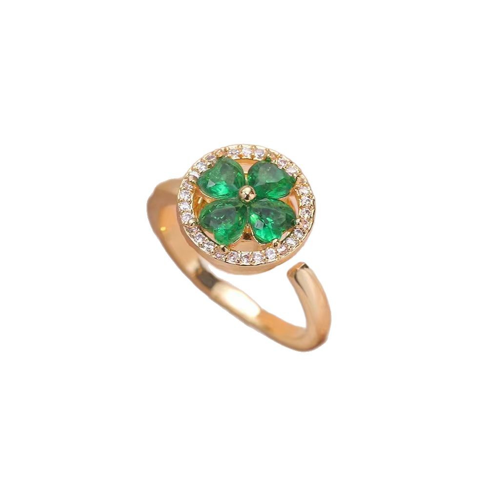 Gold ring with green gemstones on a white background