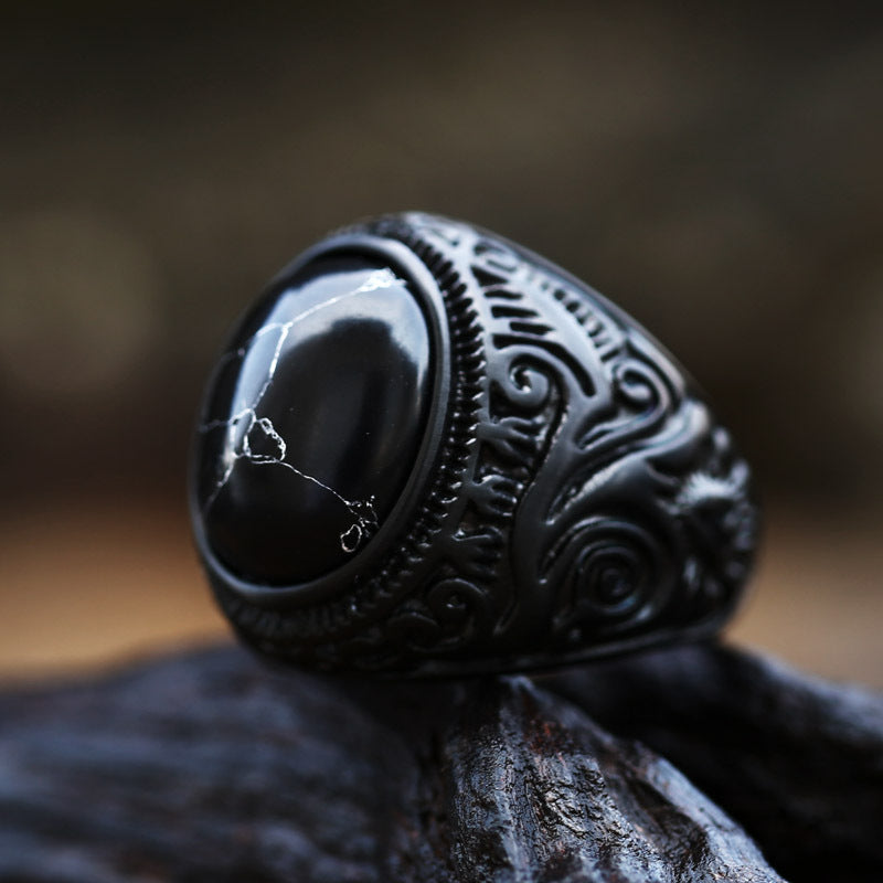 Black ring with intricate designs on a dark background