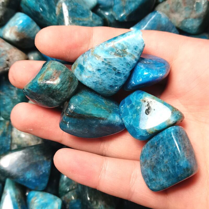 Hand holding blue stones with a background of more stones