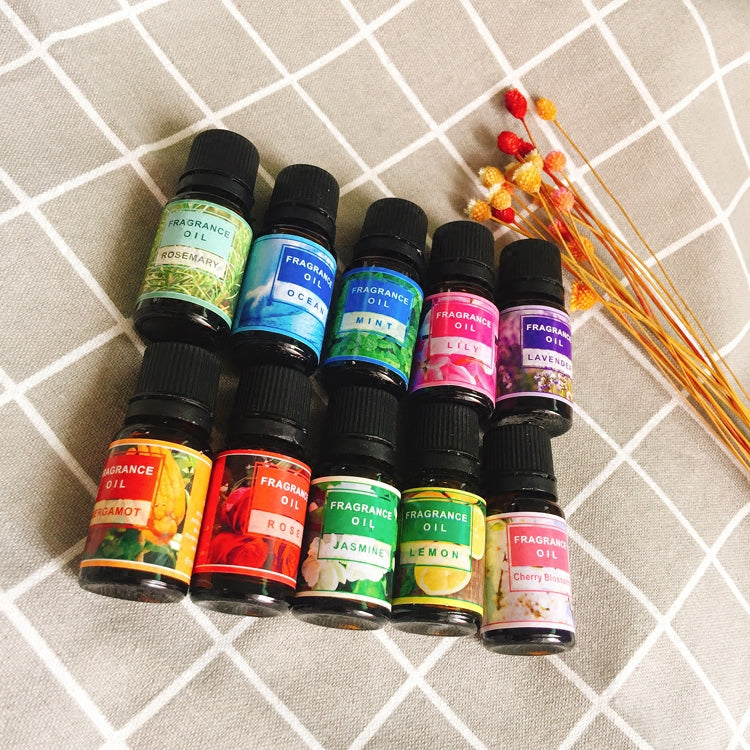 Collection of fragrance oil bottles with colorful labels on a checkered surface.