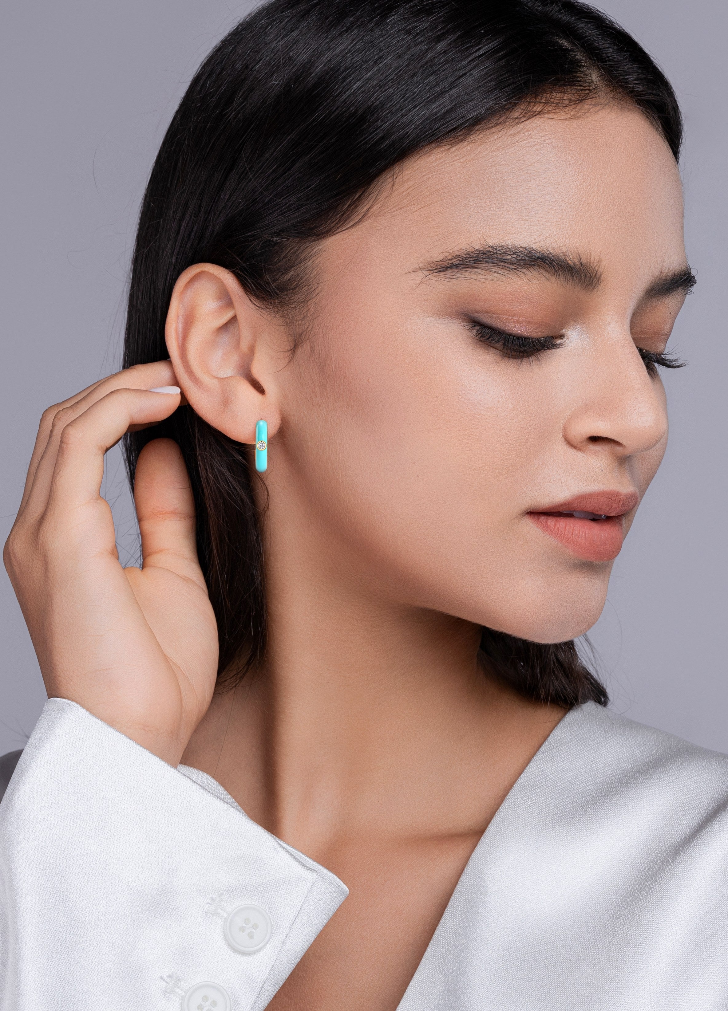 Woman wearing a turquoise earring against a neutral background
