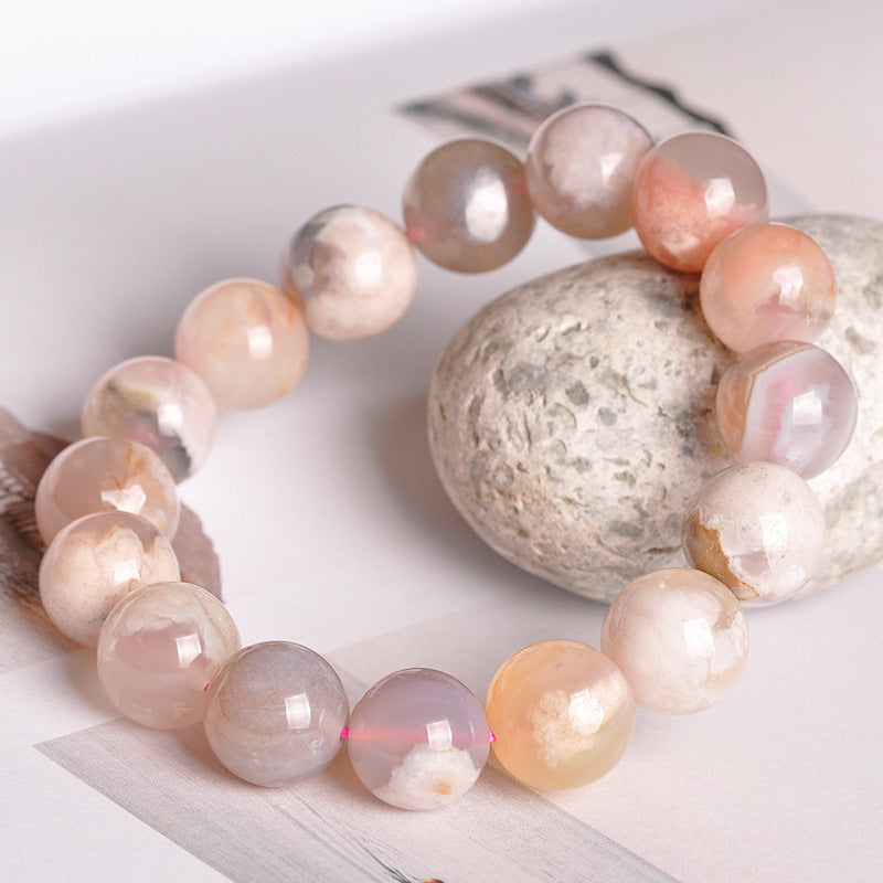 Pearl bracelet with peach and white pearls on a light wooden surface.