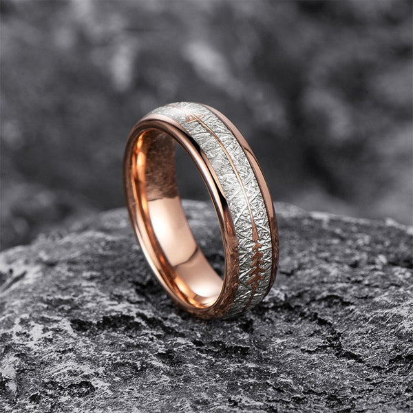 Rose gold and silver ring on a textured surface with a blurred natural background