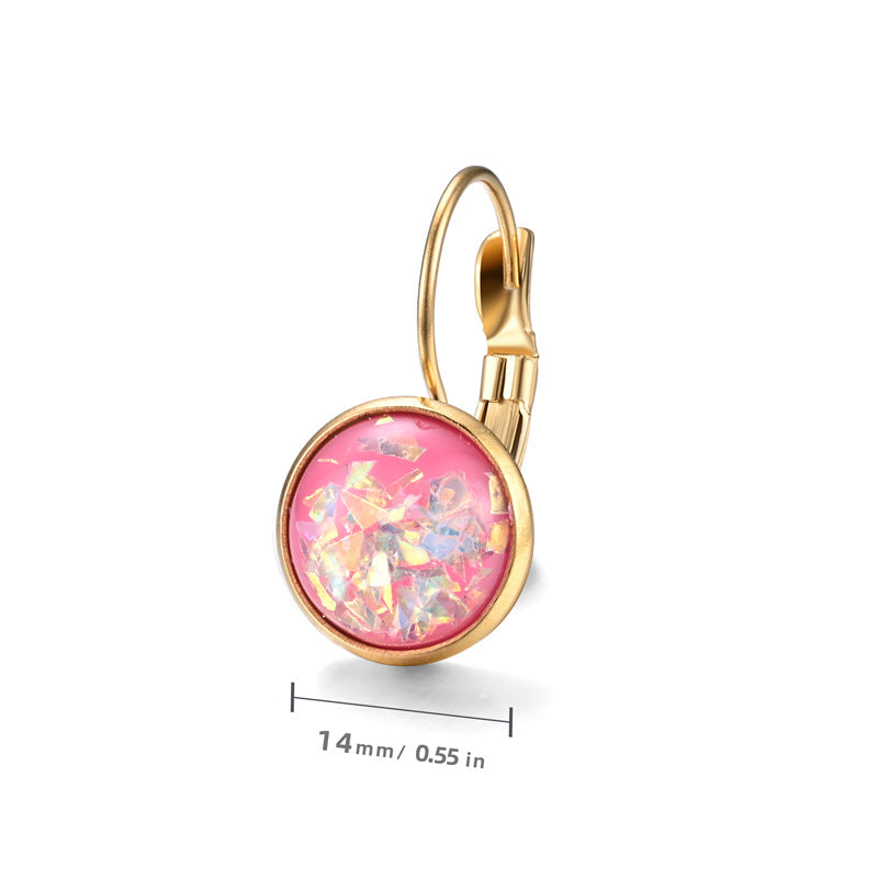 Gold earring with pink gemstone on a white background
