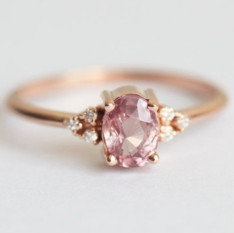 Rose gold ring with a pink gemstone on a light background