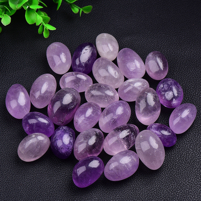 Purple and pink gemstones on a dark surface with green leaves in the corner