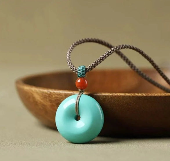 Necklace with turquoise pendant and red and blue beads on a wooden surface