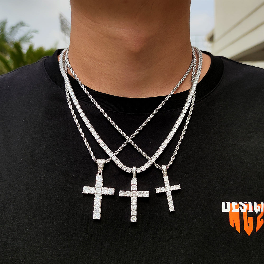Three silver cross necklaces on a person wearing a black shirt with a logo.
