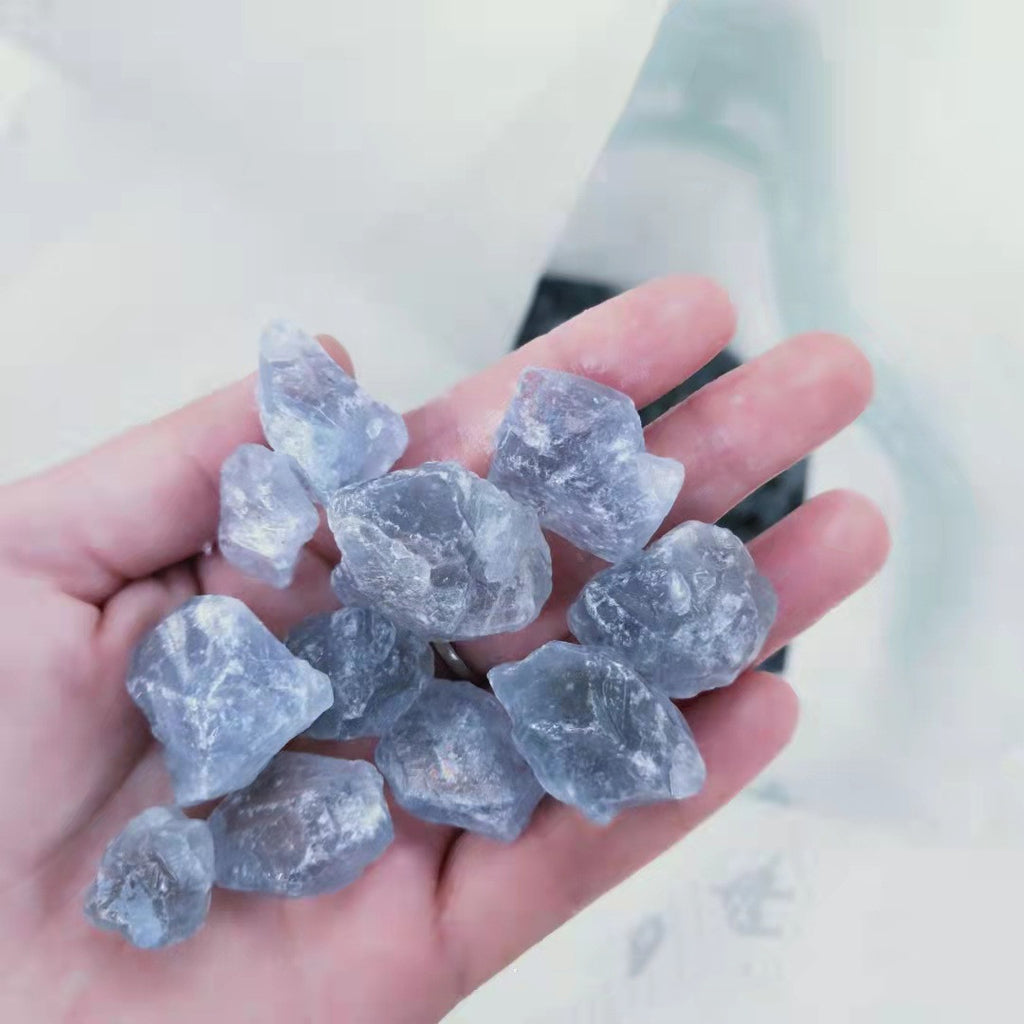 Hand holding rough diamonds against a blurred background